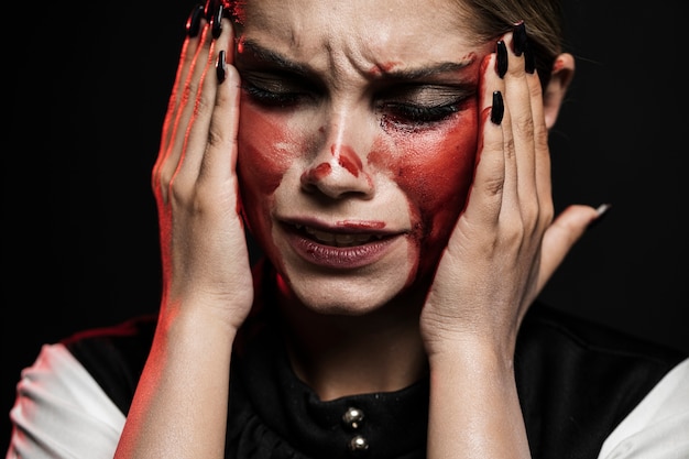 Woman with bloody makeup holding her head