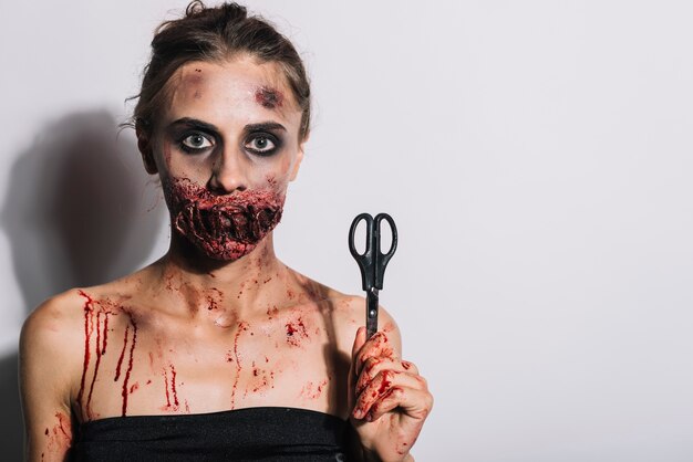 Woman with bloody sewn mouth grime and scissors