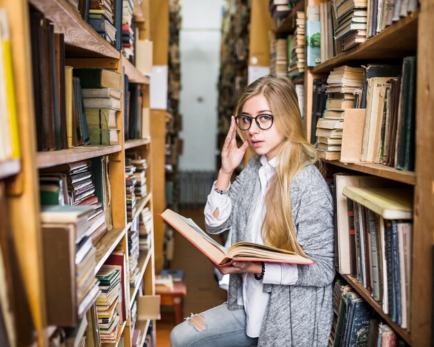 Woman with book adjusting glasses