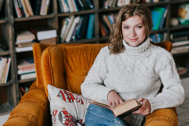 Woman with book in comfortable armchair