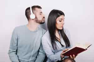 Free photo woman with book ignoring man in headphones