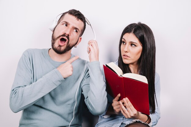 Woman with book looking at man in headphones