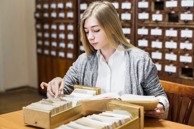 Woman with book looking through cards in drawers