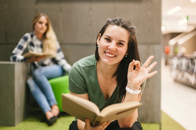 Foto gratuita donna con il libro che fa gesto okay