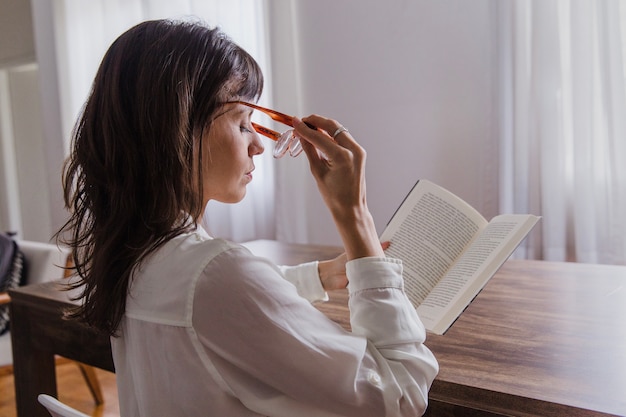 Woman with book putting on glasses