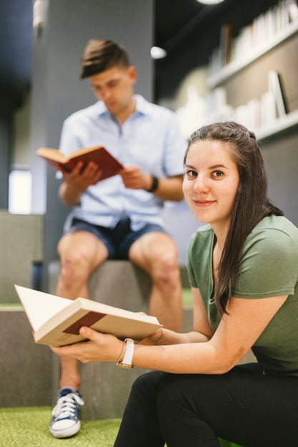 Foto gratuita donna con il libro che sorride alla macchina fotografica