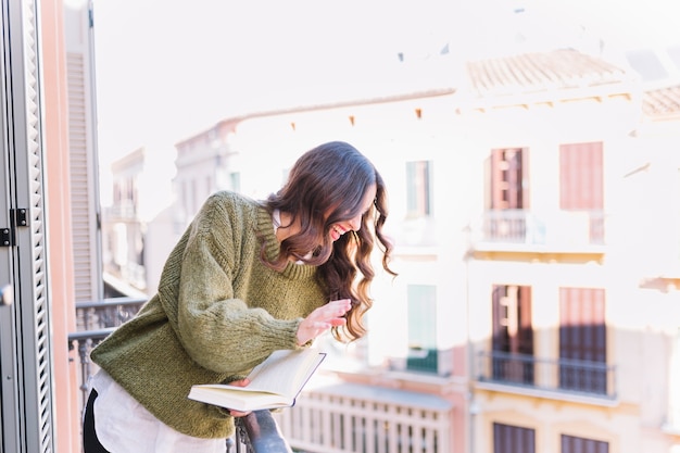 Woman with book waving hand and laughing