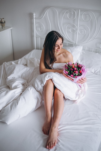 침대에서 꽃의 부케와 여자