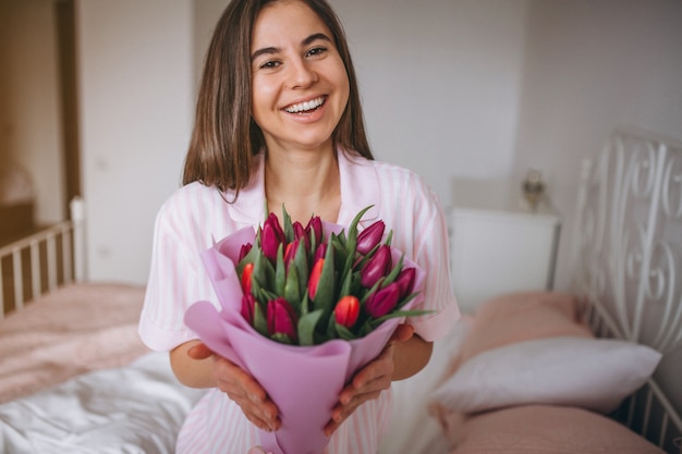 寝室で花の花束を持つ女性