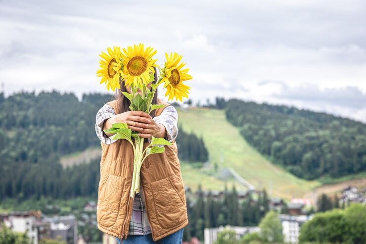Free Photo woman with a bouquet of sunflowers in nature in a mountainous area