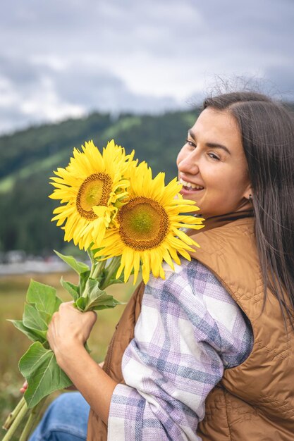 산악 지역의 자연 속에서 해바라기 꽃다발을 든 여자
