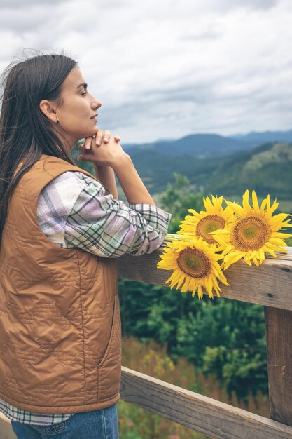 Женщина с букетом подсолнухов на природе в горах