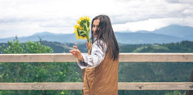 Женщина с букетом подсолнухов на природе в горах