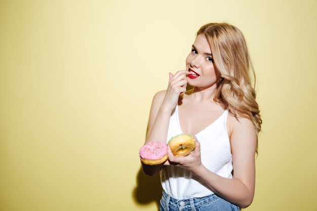 Donna con le ciambelle luminose della tenuta di trucco delle labbra