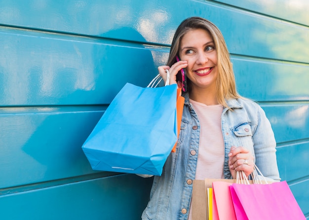 Woman with bright shopping bags talking by phone