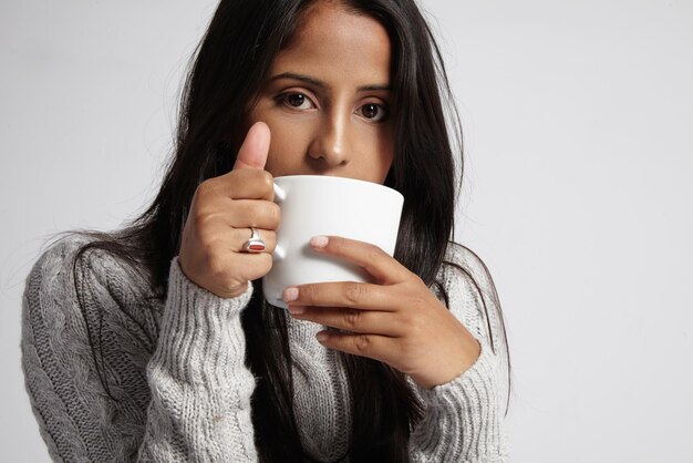 Woman with brunette straight hair drinks hot coffe at cold time