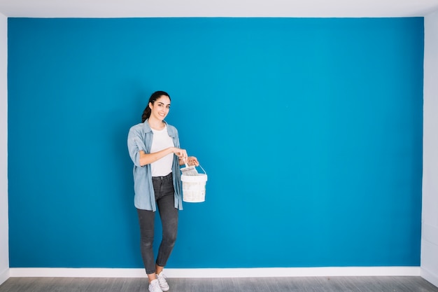 Foto gratuita donna con il secchio davanti alla parete