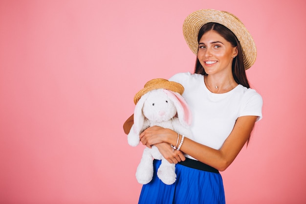 Woman with bunny toy on pink background