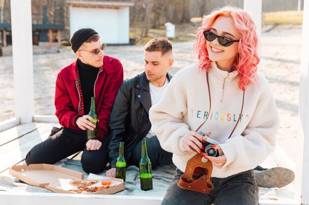 Woman with camera and couple of man on picnic