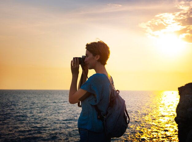 Woman with camera shooting on the beach