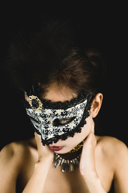 Woman with a carnival mask on a dark background