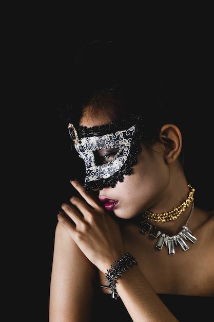 Woman with a carnival mask on a dark background