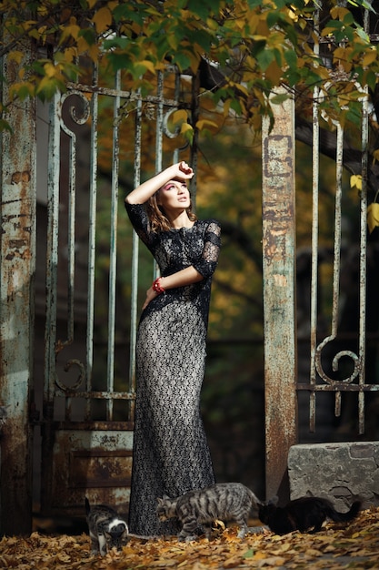 Woman with cats and a rusty iron fence