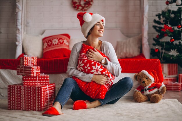 Woman with Christmas presents by Christmas tree