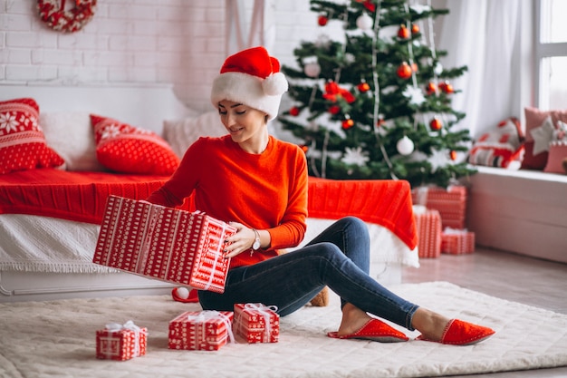 Женщина с рождественскими подарками у елки