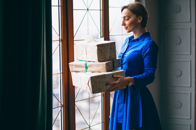Woman with christmas presents standing by the window