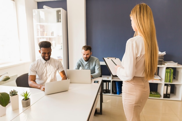 Woman with clipboard near male colleagues