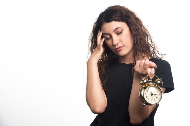 Woman with clock holding her head on white background. High quality photo