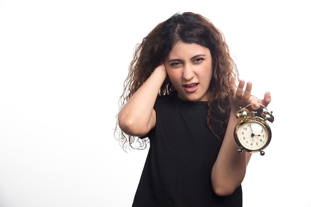 Woman with clock holding her head on white background. High quality photo