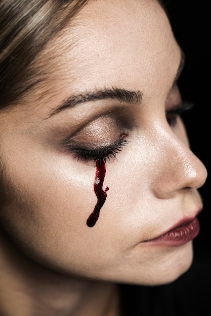 Woman with closed eyes and blood make-up