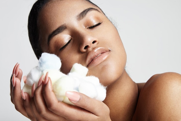 Free photo woman with closed eyes clasp to a face soft cotton balls