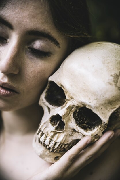 woman with closed eyes holding skull