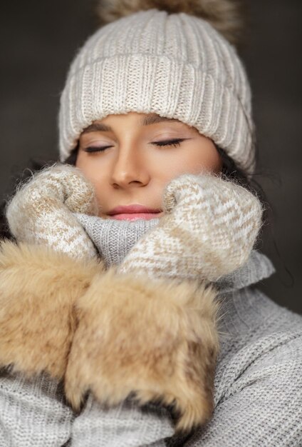 暖かい冬の服と毛皮の手袋で目を閉じた女性。