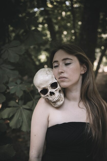 Женщина с закрытыми глазами с декоративным черепом человека на плече