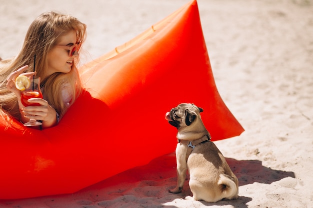 Woman with coctail lying on a pool mattress at the beach