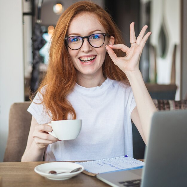 Woman with coffee cup showing okay gesture 