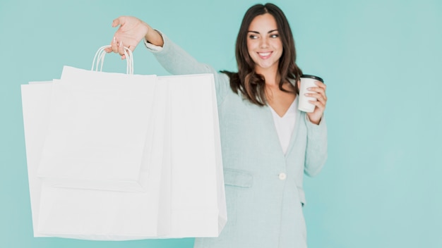 Woman with coffee and shopping bags on a blue background