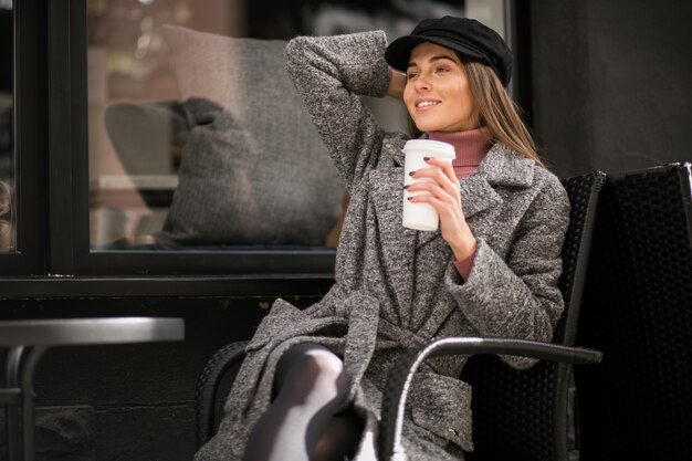 Woman with coffee sitting outside the cafe