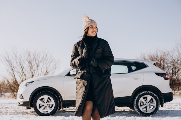 Женщина с кофе, стоя на машине в зимнем поле