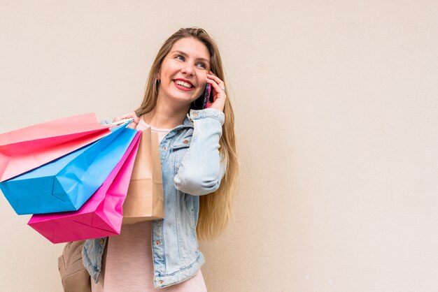 Woman with colourful shopping bags talking by phone