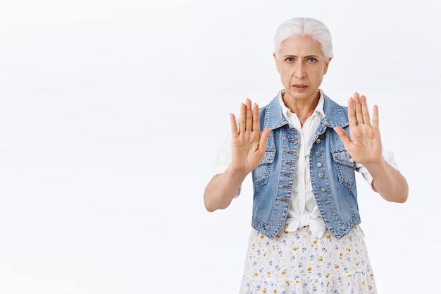 woman with combed grey hair, raise hands in stop, taboo or refusal motion, frowning distressed want to finish something, give warning