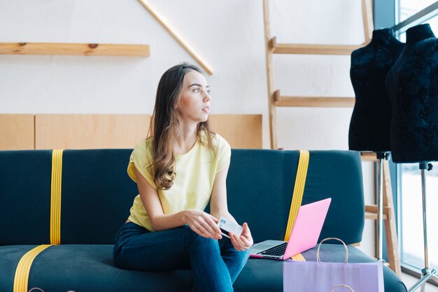 Woman with credit card sitting near laptop