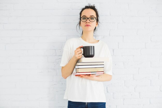 Woman with cup and books looking at camera