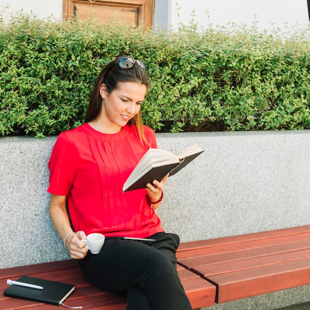 Free photo woman with cup of coffee reading book