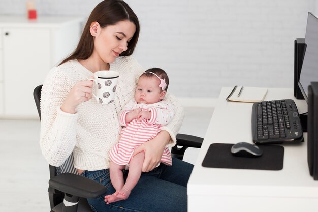 Женщина с чашкой и дочерью в офисе