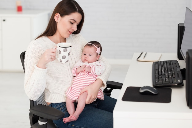 Женщина с чашкой и дочерью в офисе